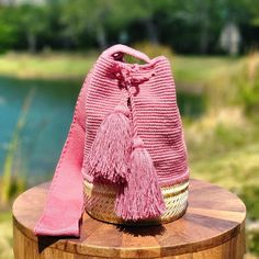 a pink handbag sitting on top of a wooden table next to a lake with trees in the background