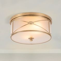 a ceiling light with a white shade on it's side and a gold finish