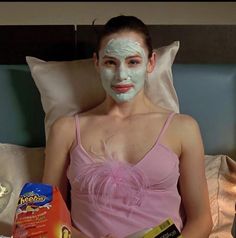 a woman in a pink dress is sitting on a bed with her face mask on