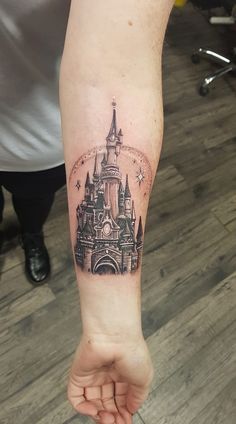 a woman's arm with a castle tattoo on it