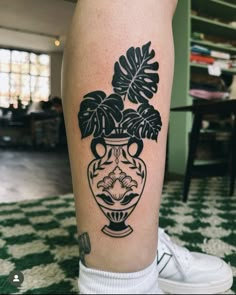 a black and white photo of a vase with plants in it on the leg,