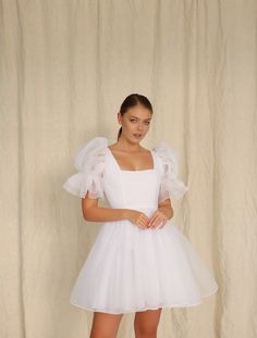 a woman in a white dress posing for the camera with her hands on her hips