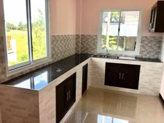 an empty kitchen with black counter tops and white tile backsplashes on the walls