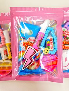 two pink plastic bags filled with candy and other candies, including toothbrushes