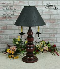 a table lamp sitting on top of a white carpet next to flowers and plants in front of a brick wall