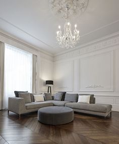 an elegant living room with white walls and wood flooring, chandelier hanging from the ceiling