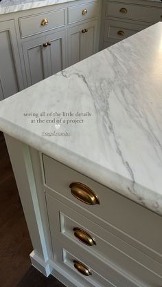 a white marble counter top in a kitchen with gold pulls on the handles and drawers