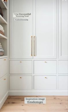 an empty closet with white cabinets and gold pulls on the doors, in front of a wooden floor