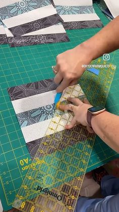 a person cutting fabric with scissors on top of a piece of green paper next to a pair of scissors