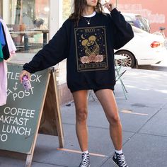 a woman is standing on the sidewalk with an umbrella in her hand and wearing a black sweatshirt