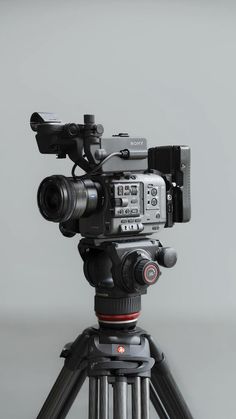 a video camera sitting on top of a tripod in front of a gray wall