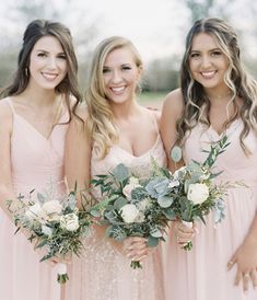 three bridesmaids in pink dresses holding bouquets with greenery and flowers on them