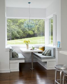 a room with two benches and a table in front of a window overlooking a field