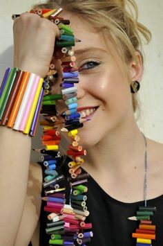 a woman is holding up many colored pencils