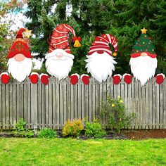 three garden gnomes on top of a wooden fence