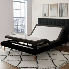 a black bed frame with a white mattress on it in front of a large window