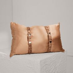 a brown pillow sitting on top of a white wall next to a black and silver object