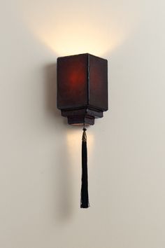 a wall mounted light with a tassel hanging from it's side on a white wall