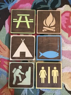 four wooden signs with different types of symbols on them sitting on a carpeted surface