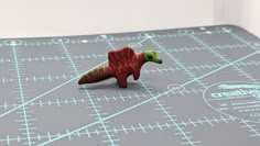 a red toy dinosaur on a cutting board with blue and white lines around it's edges