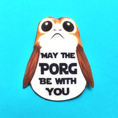 a close up of a brooch on a blue background with the words may the porg be with you