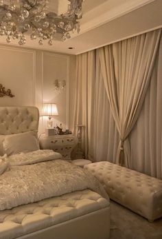 a white bed sitting in a bedroom under a chandelier