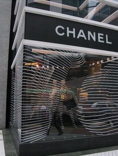 a store front with the word chanel on it's glass display window and people walking by