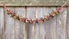 a garland made out of dried flowers hanging from a wooden fence with red and yellow ribbons