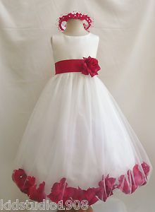 a white dress with red flowers on the skirt and a pink flower in the center