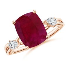 a ring with an oval ruby stone and two diamonds on the band, set in yellow gold