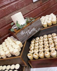 there are many cupcakes on display in the wooden box and one has a wedding cake