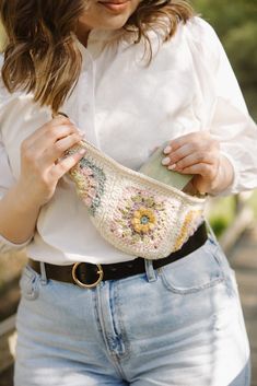 a woman in white shirt and jeans holding a purse