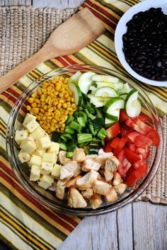 a glass bowl filled with chopped vegetables and black beans