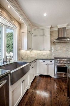 a kitchen with wooden floors and white cabinets, stainless steel sink and dishwasher