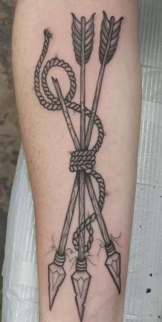 a black and white tattoo with arrows on the leg, an arrow is tied up to it