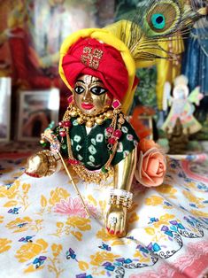 a small doll sitting on top of a table next to a peacock headdress