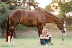 a woman kneeling down next to a brown horse