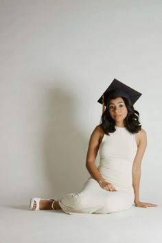 a woman sitting on the ground wearing a graduation cap