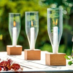 three candles are placed in wooden holders on a table