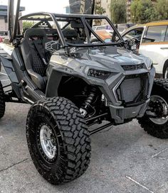 a silver four - wheeled vehicle parked in a parking lot with other vehicles behind it