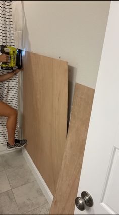 a woman is working on the wall in her bathroom while holding a drill and screwdriver