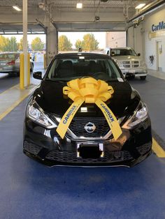 a car with a yellow ribbon tied to it's hood in a parking garage