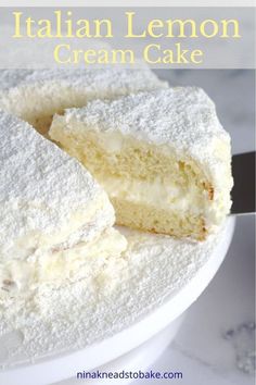 a white cake with powdered sugar on top is cut in half and sits on a plate