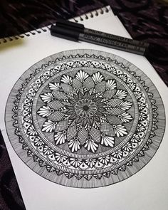 a black and white drawing on top of a paper with a pen next to it