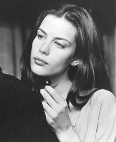 black and white photograph of a woman holding her hand up to her face while looking off into the distance