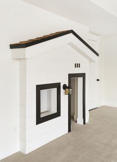 a white dog house with black trim and windows on the top floor is in an empty room