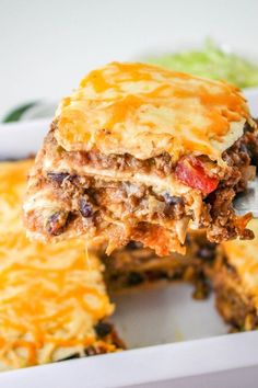 a piece of lasagna being lifted from a casserole dish with cheese