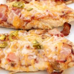 two pieces of chicken covered in cheese and toppings on a white plate with green peppers