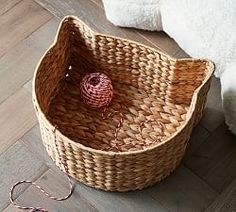 a basket with yarn in it sitting on the floor next to a white teddy bear