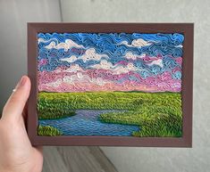 a person holding up a card with a painting on it